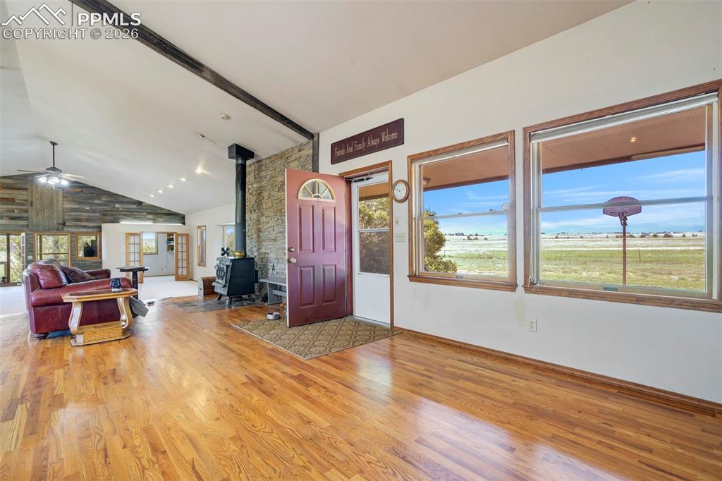 Image 15 of 50: Hardwood flooring throughout a spacious room featuring a vaulted ceiling wi