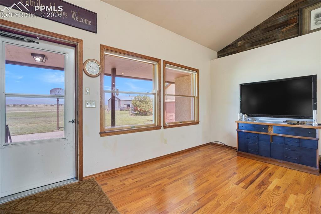 Image 16 of 50: Hardwood flooring extends throughout the living area, featuring a vaulted c