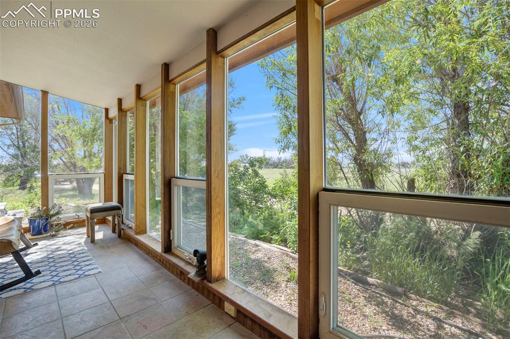 Image 24 of 50: Sunroom featuring extensive window-lined walls, natural wood-finish framing
