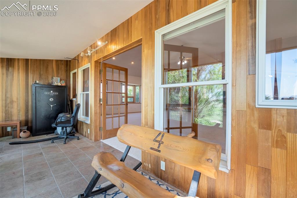 Image 25 of 50: Enclosed patio featuring extensive wood paneling, large white-framed window