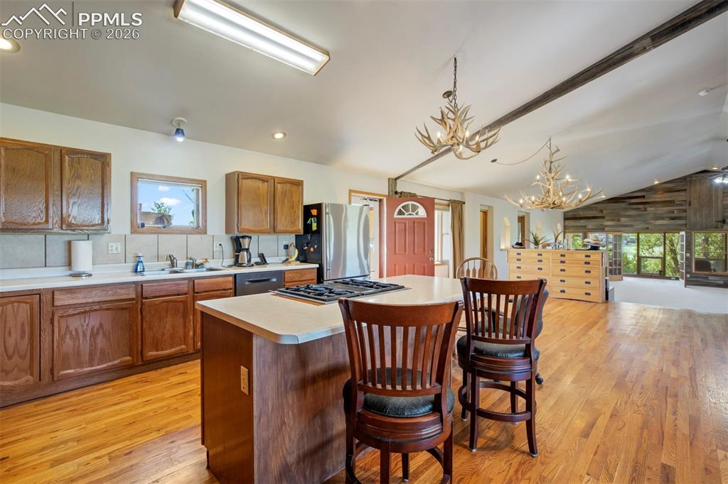 Image 26 of 50: Open-concept kitchen featuring wood cabinetry, a central island with integr
