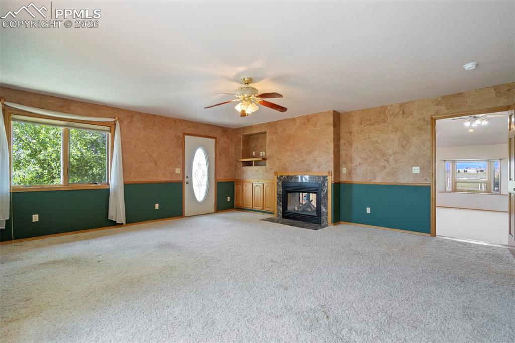 Image 34 of 50: Spacious living area featuring light-colored carpeting and a ceiling fan