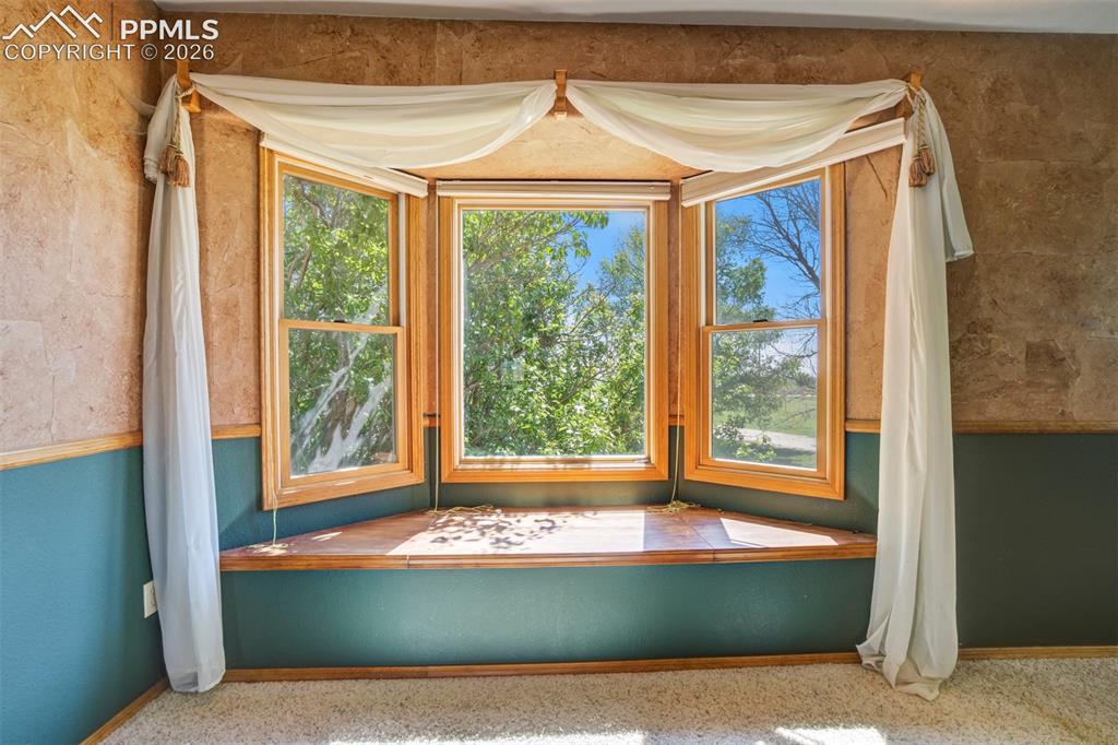 Image 35 of 50: Bay window with natural wood trim, integrated window seat, textured wall fi