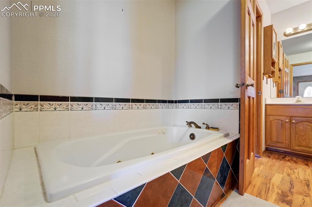 Image 36 of 50: Built-in soaking tub with brass fixtures, surrounded by white tile with a d