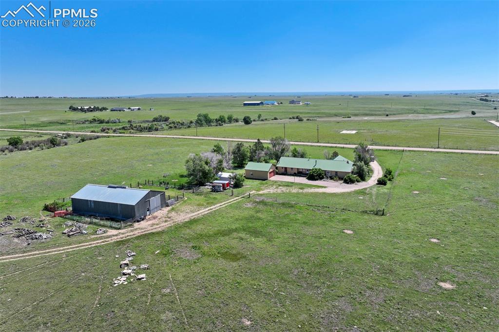 Image 4 of 50: Ranch-style residence featuring a green metal roof, a gravel driveway, and