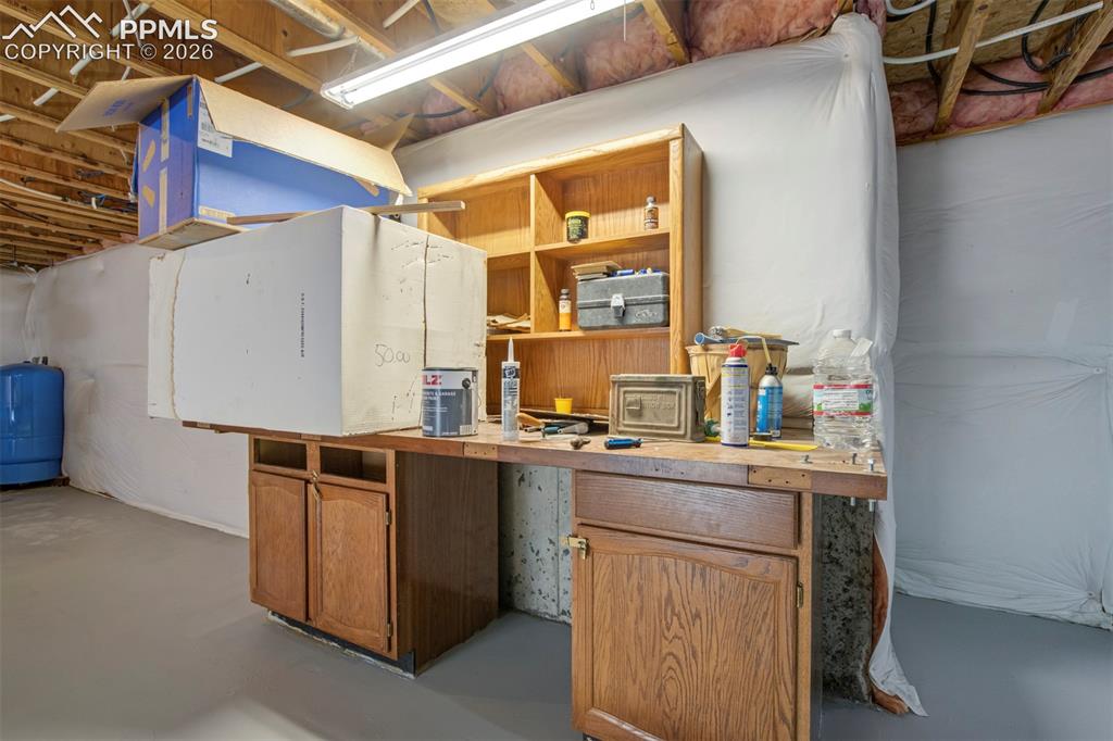 Image 45 of 50: Utility space featuring unfinished ceiling joists, concrete flooring, and a