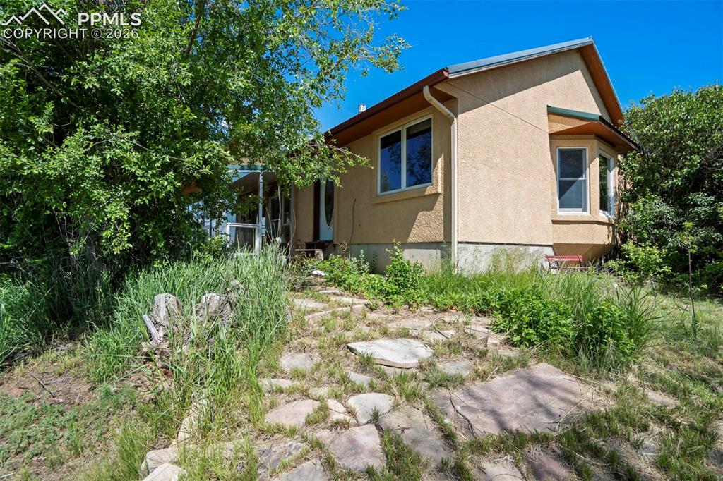 Image 49 of 50: Stucco exterior featuring a bay window, rain gutters, and an entrance with