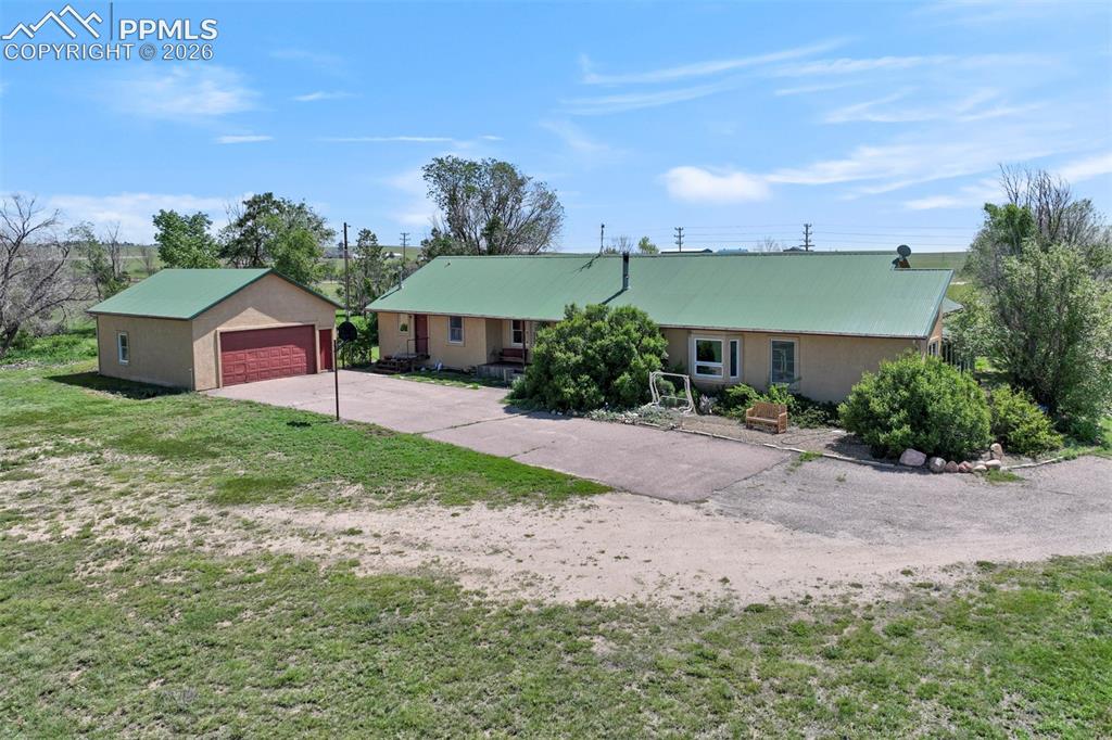 Image 9 of 50: Ranch-style residence featuring a green metal roof and a detached garage wi