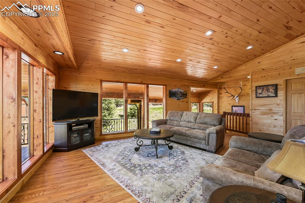 Image 13 of 50: Living area with vaulted ceiling, wood walls, and wood ceiling