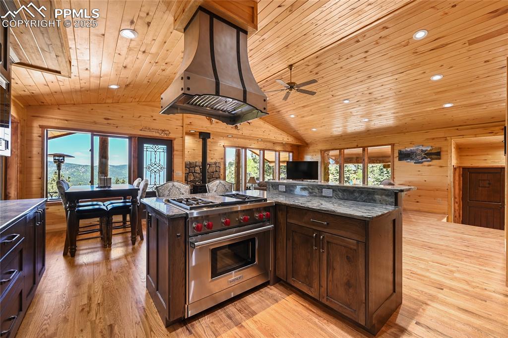 Image 17 of 50: Kitchen with wall chimney range hood, wooden ceiling, premium stove, and wo