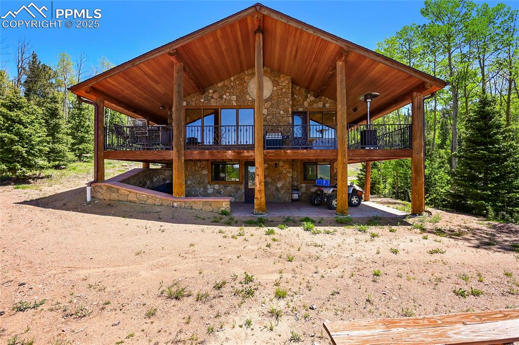 Image 2 of 50: Back of property with a patio area, a wooden deck, and stone siding