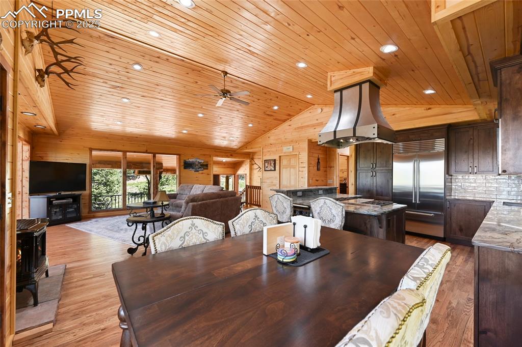 Image 20 of 50: Dining room featuring high vaulted ceiling, light wood finished floors, woo