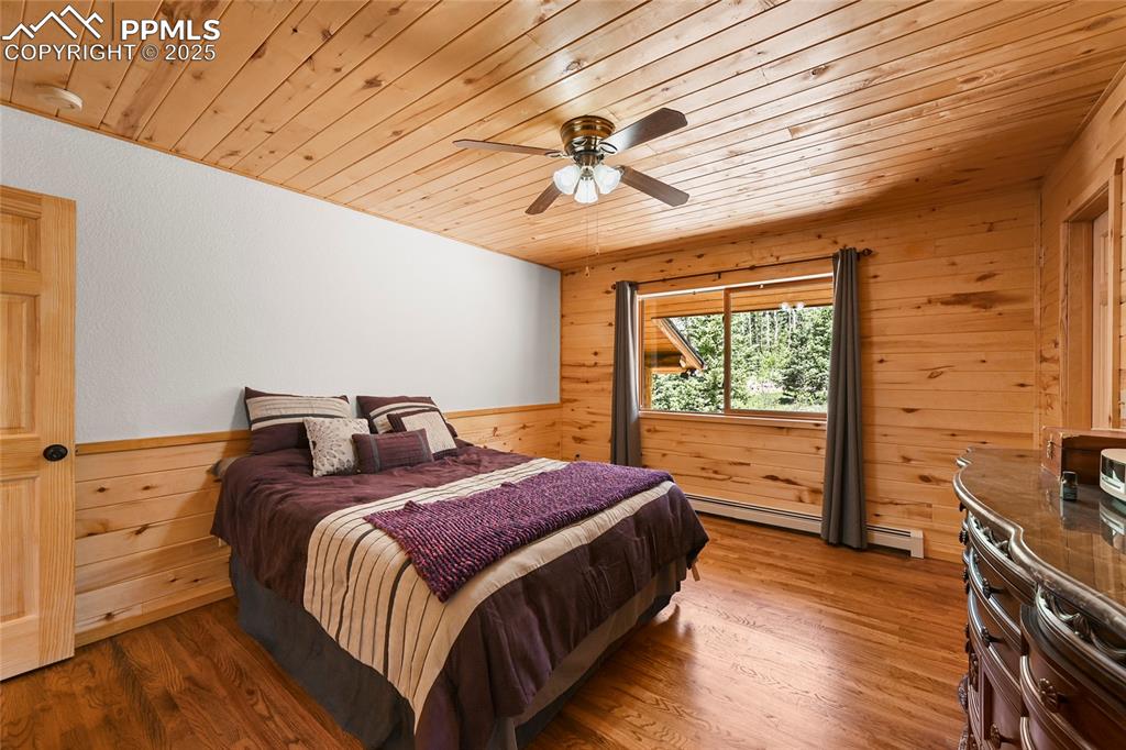Image 22 of 50: Bedroom featuring wood ceiling, wooden walls, and wood finished floors