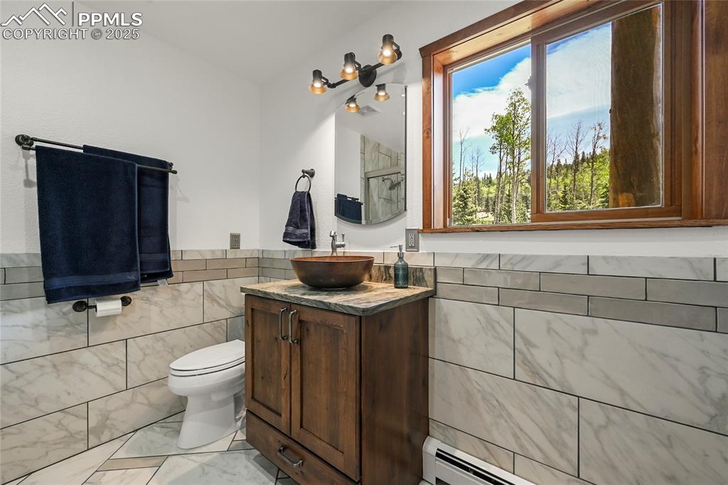 Image 24 of 50: Bathroom with toilet, vanity, a baseboard radiator, marble finish floor, an