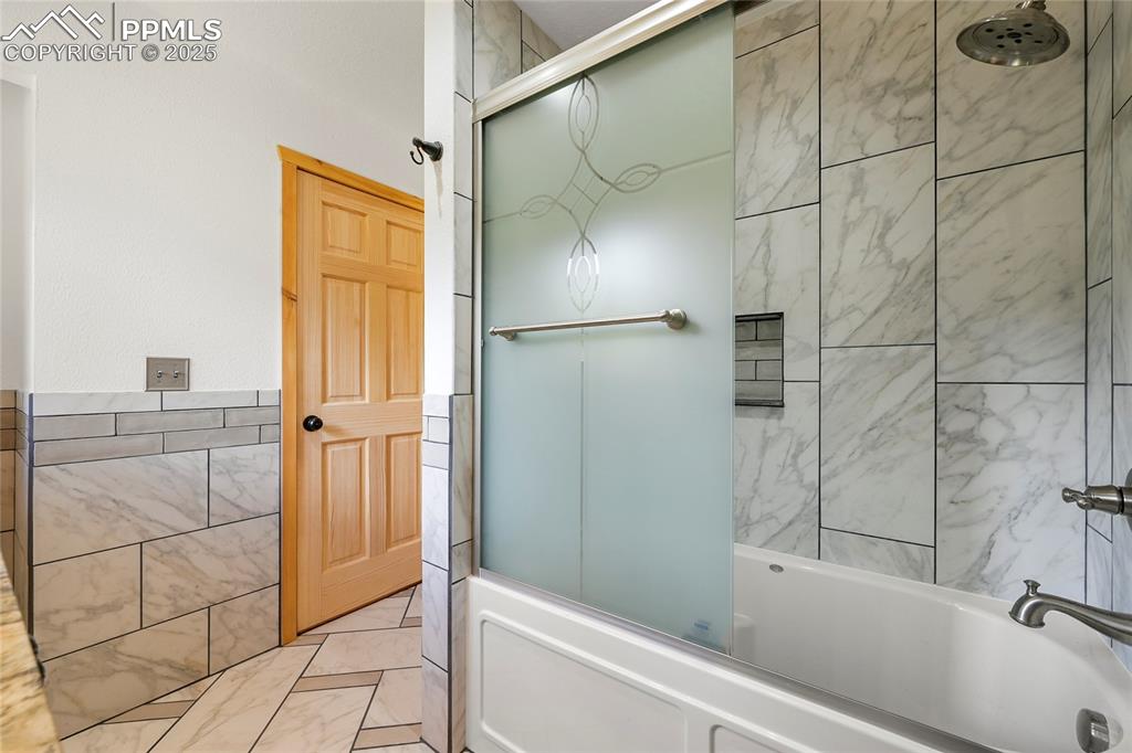 Image 26 of 50: Full bathroom featuring bathtub / shower combination and tile walls