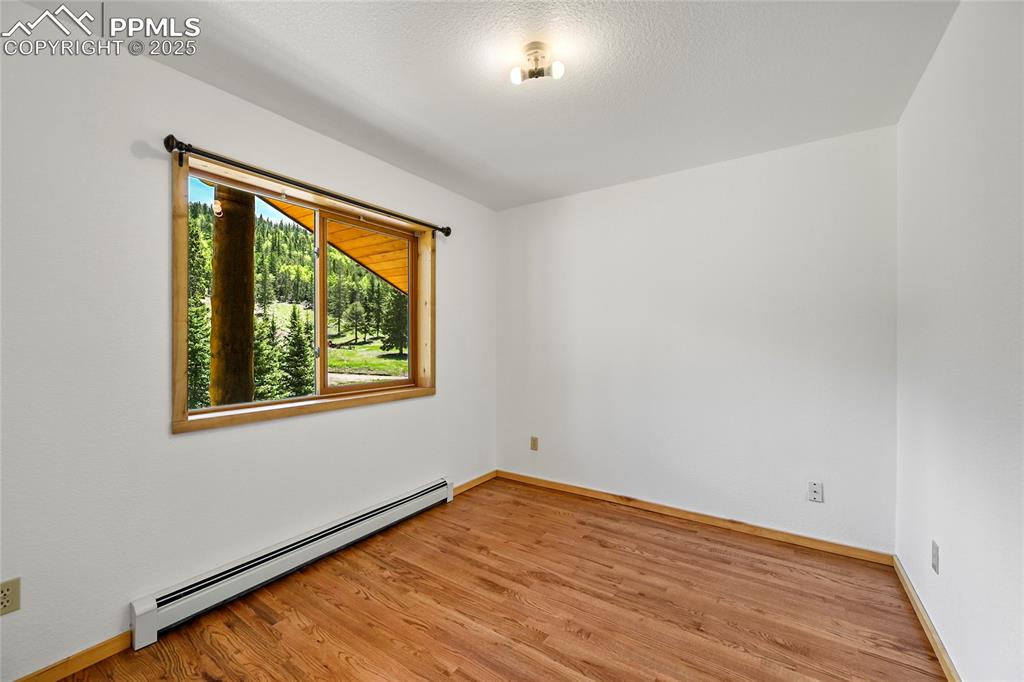 Image 27 of 50: Unfurnished room featuring a baseboard radiator, baseboards, and light wood