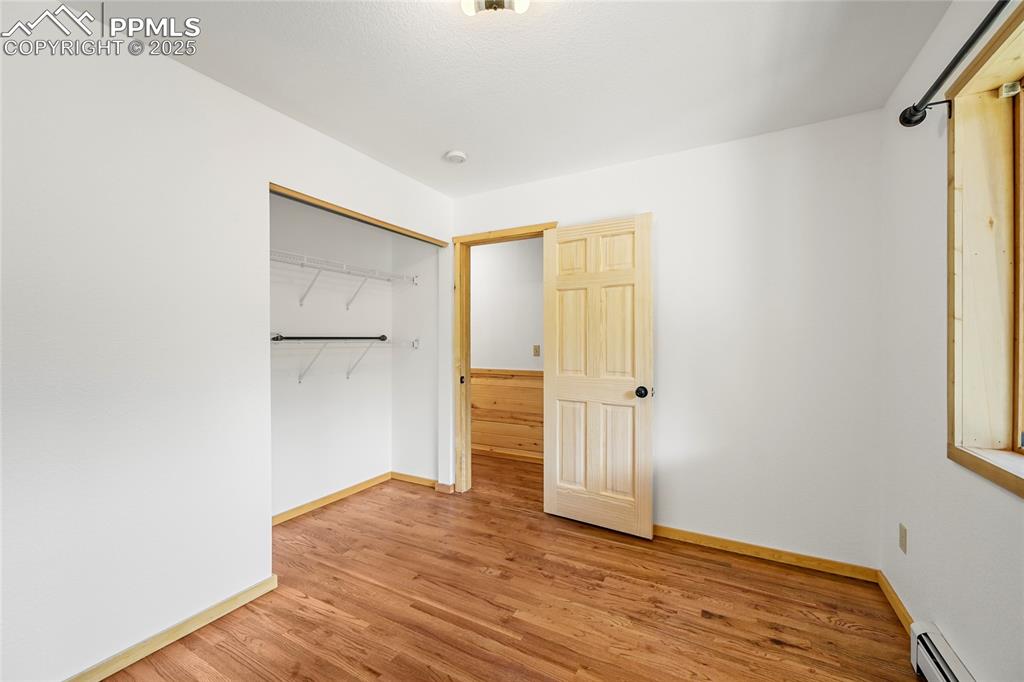 Image 28 of 50: Unfurnished bedroom with baseboards, a closet, a baseboard heating unit, an