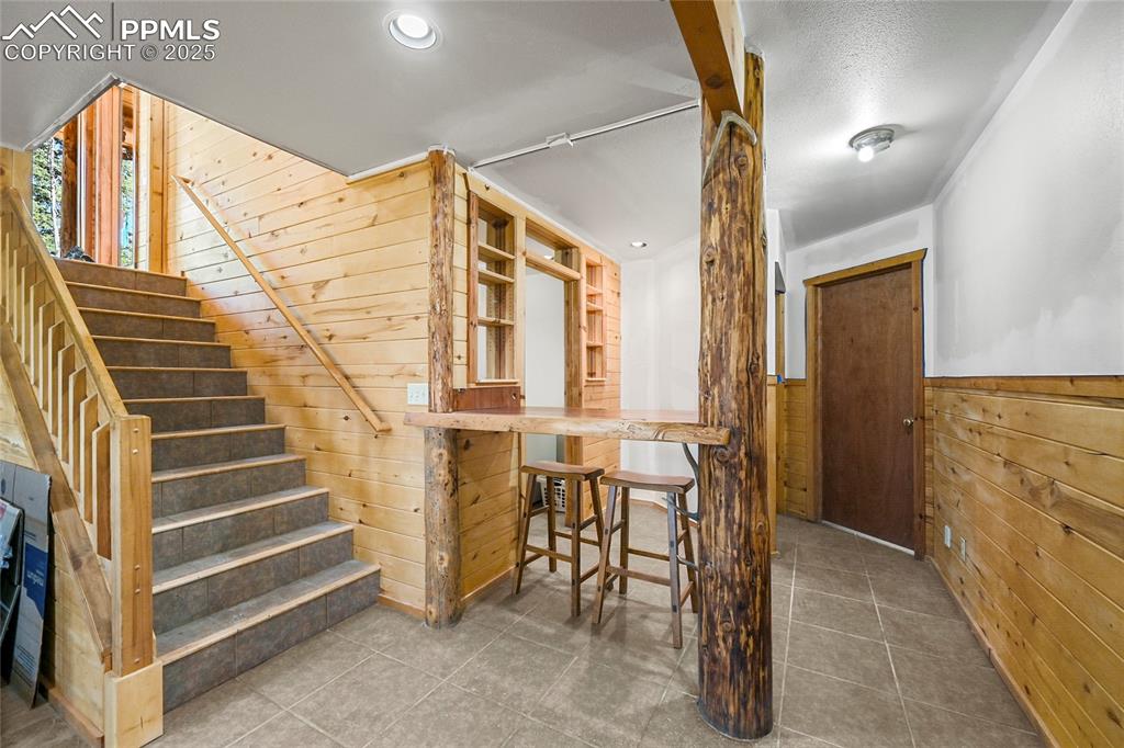 Image 33 of 50: Staircase featuring tile patterned floors, wooden walls, and wainscoting