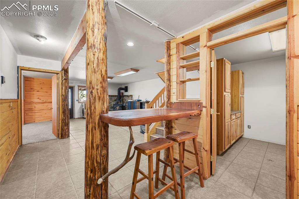 Image 34 of 50: Dining space featuring a wainscoted wall, wood walls, stairs, and light til