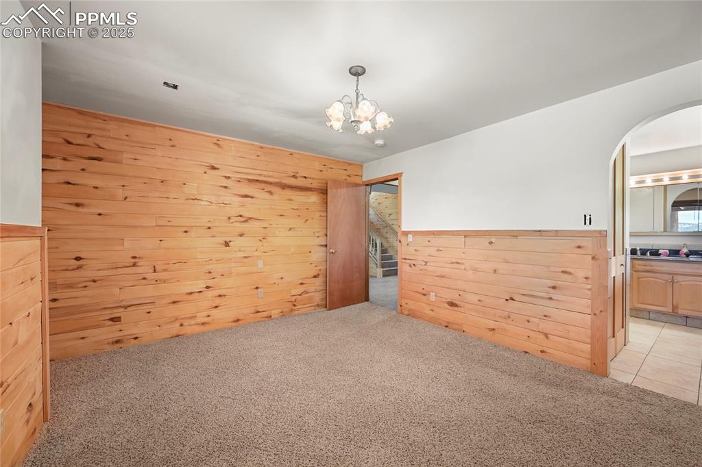Image 41 of 50: Empty room with a wainscoted wall, a chandelier, wooden walls, arched walkw