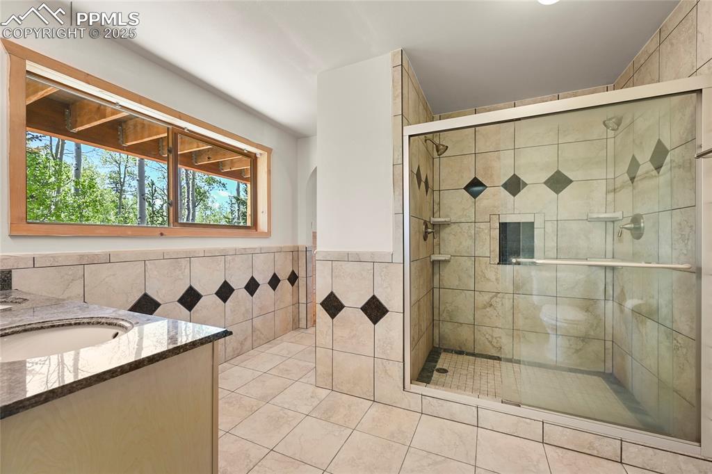 Image 43 of 50: Full bathroom featuring tile walls, vanity, and a shower stall