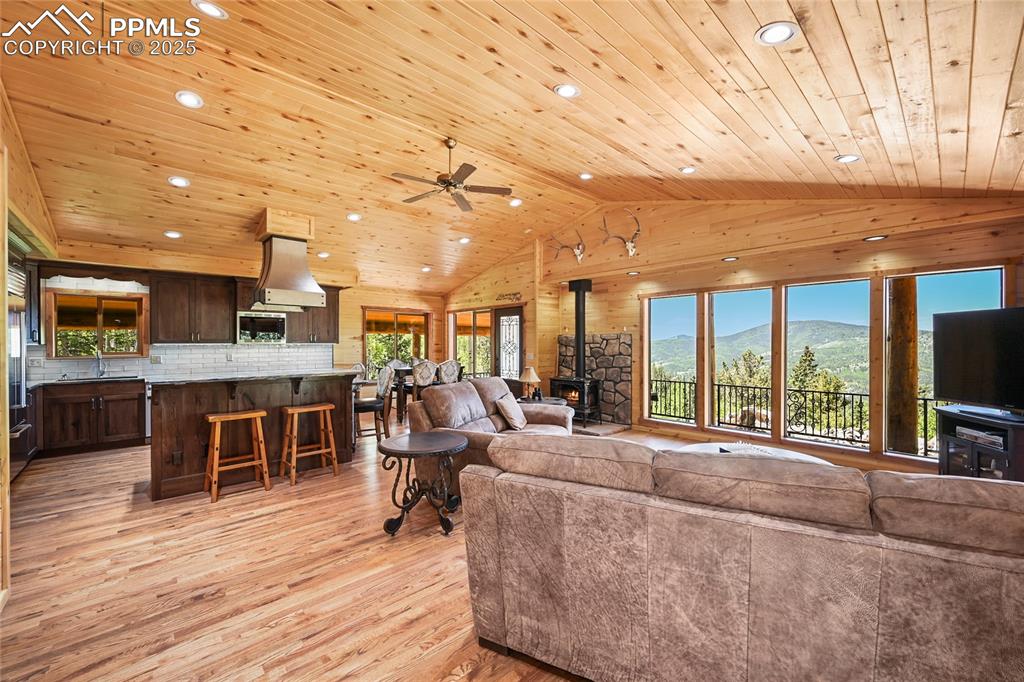 Image 9 of 50: Living room featuring wooden ceiling, a wood stove, lofted ceiling, light w