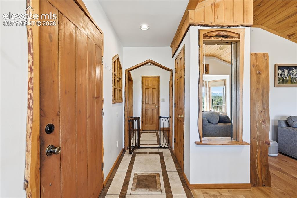 Image 12 of 49: View near front door toward kitchen area. Notice the custom woodworking.