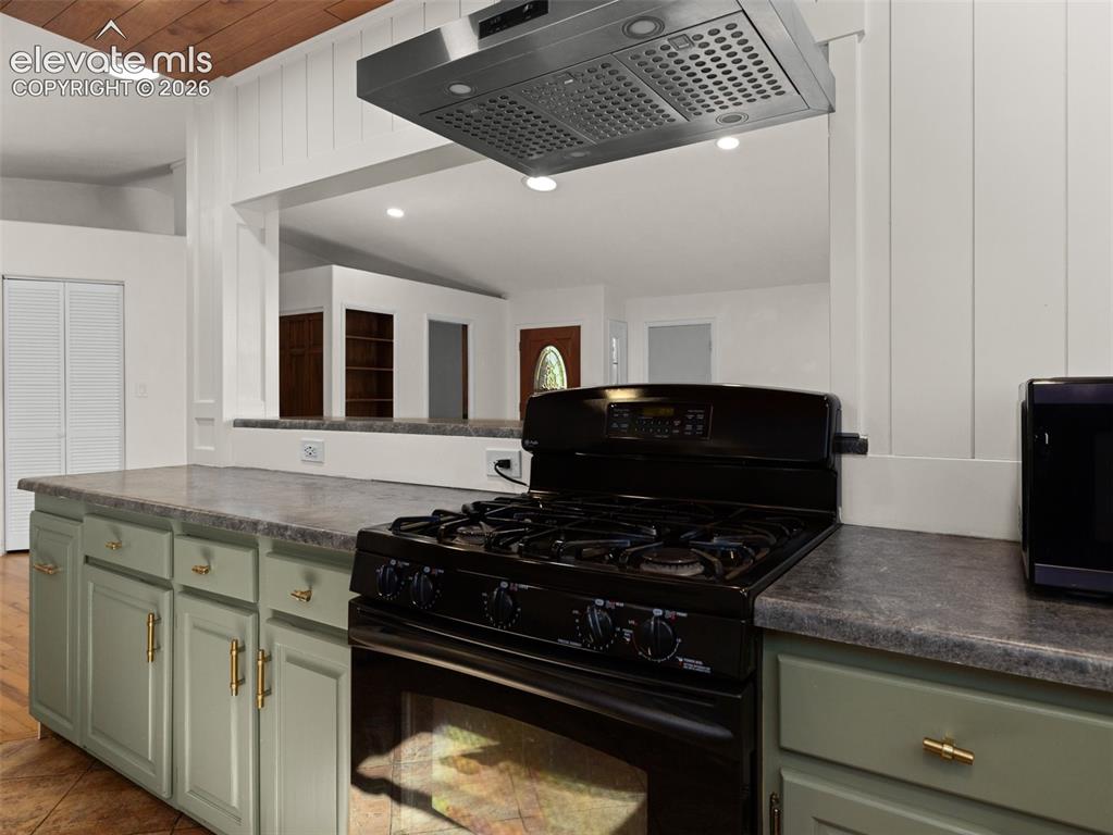 Image 10 of 35: Kitchen featuring a black gas range with an overhead stainless steel range 