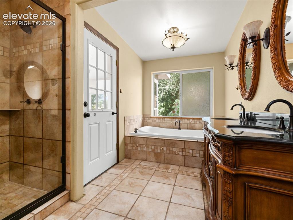 Image 16 of 35: Bathroom featuring a large soaking tub with tiled surround, a separate glas
