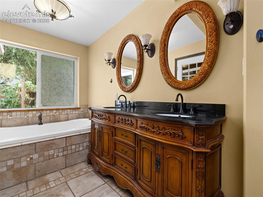 Image 17 of 35: Dual oval mirrors with ornate frames above a carved wood-finish vanity with