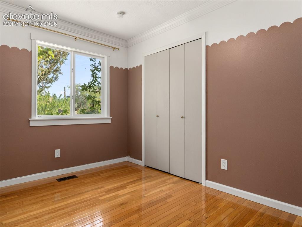 Image 18 of 35: Room featuring warm-toned walls with a scalloped border, wood-finish floori