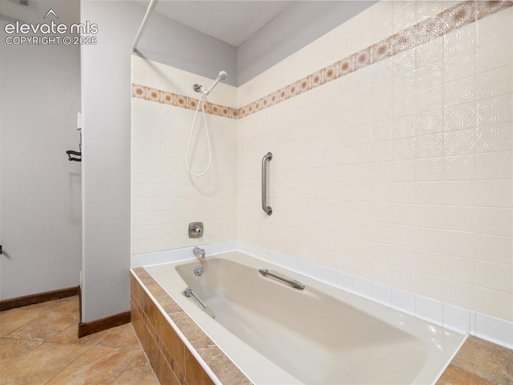 Image 20 of 35: Built-in bathtub featuring a showerhead with flexible hose, a grab bar, and