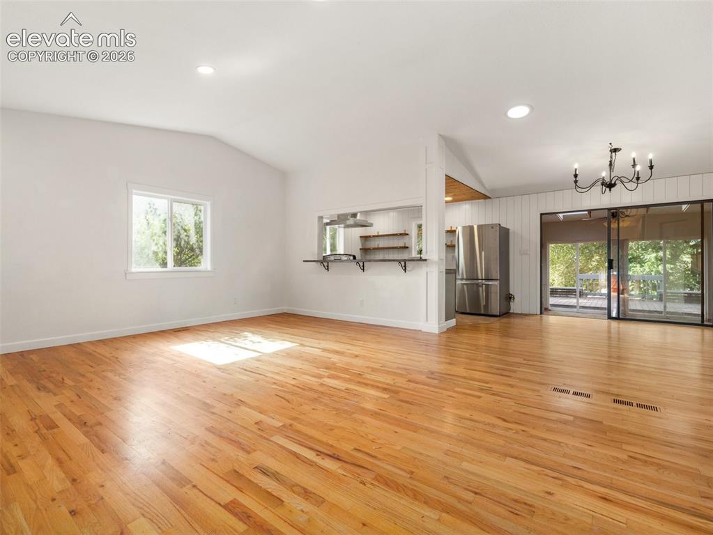 Image 3 of 35: Spacious open-concept living area featuring wood-finish flooring, vaulted c