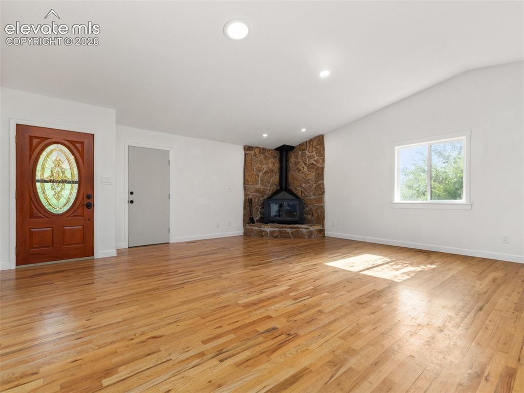 Image 6 of 35: Spacious interior featuring wood-finish flooring, a stone-clad fireplace wi