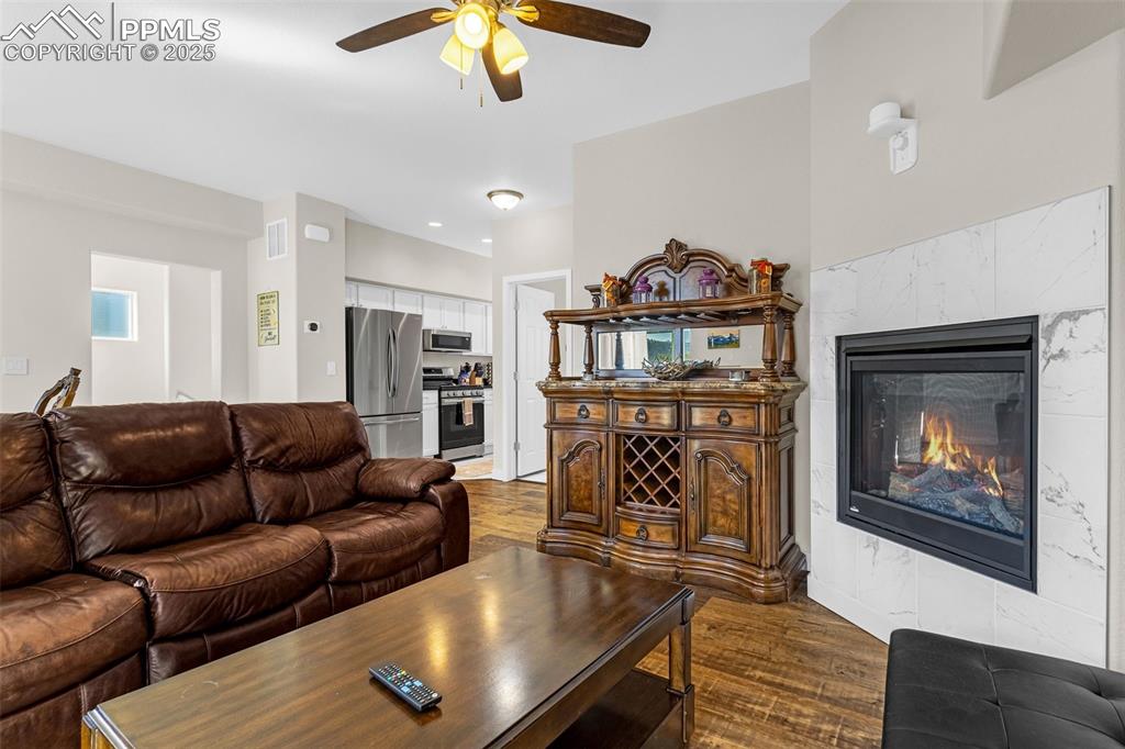 Image 6 of 37: Living room with a tiled fireplace, dark wood-style floors, visible vents,