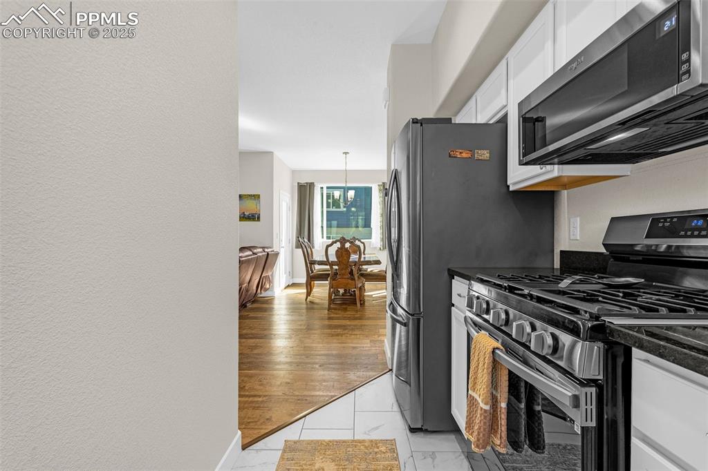 Image 9 of 37: Kitchen with dark countertops, white cabinets, appliances with stainless st