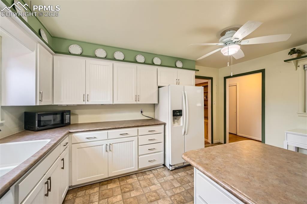 Image 14 of 33: Kitchen featuring white fridge with ice dispenser, black microwave, a ceili