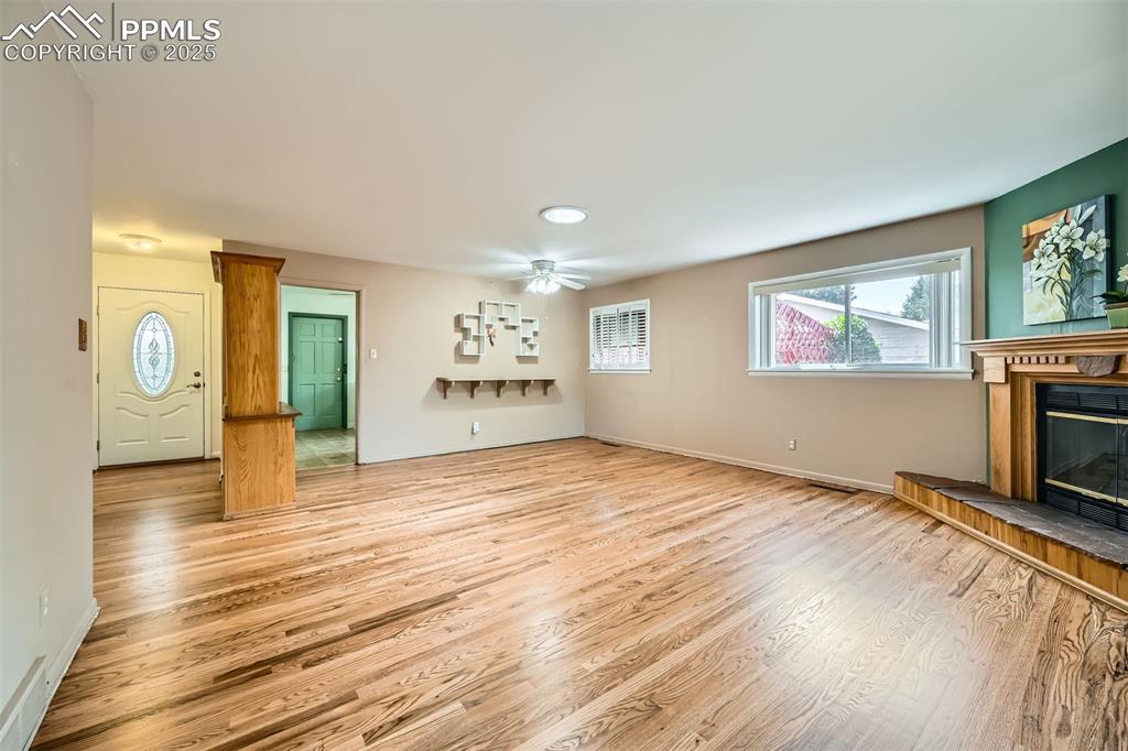 Image 9 of 33: Unfurnished living room with light wood-type flooring, a glass covered fire