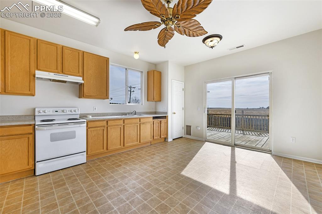 Image 11 of 28: Kitchen with white electric stove, a ceiling fan, and light countertops