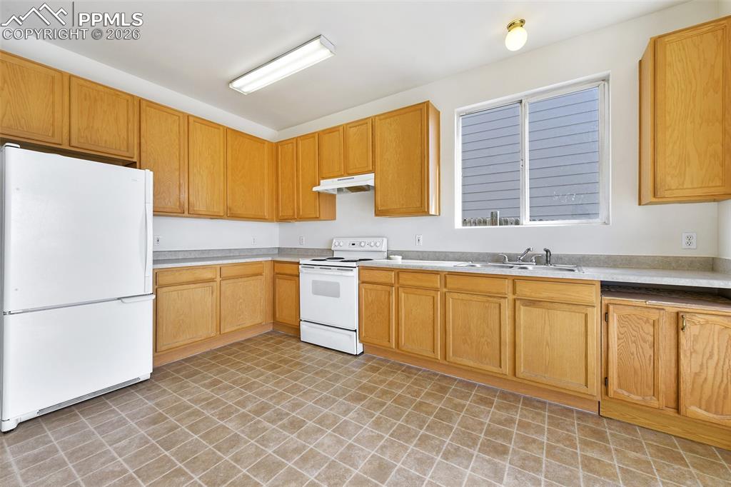 Image 13 of 28: Kitchen with white appliances and light countertops