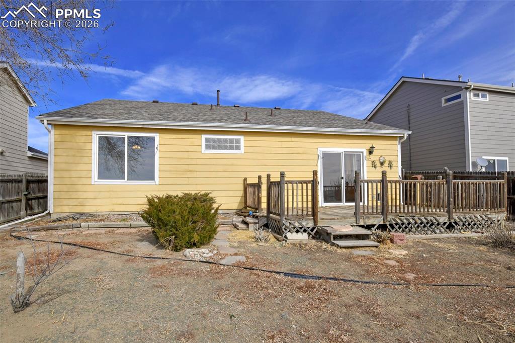 Image 26 of 28: Rear view of house with a wooden deck and roof with shingles