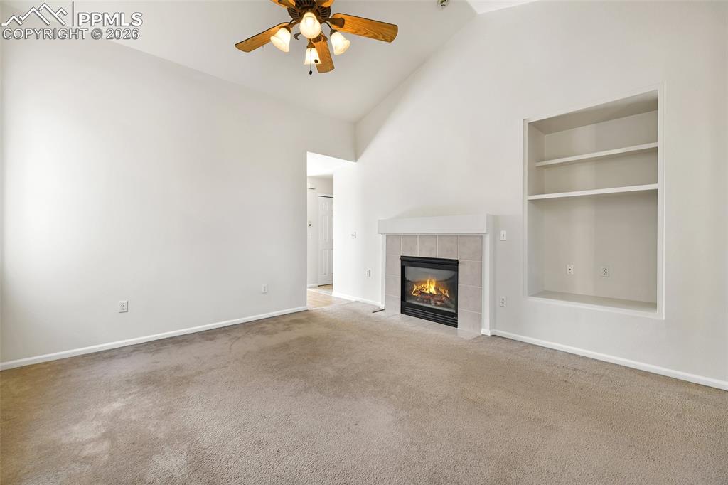 Image 5 of 28: Unfurnished living room featuring a ceiling fan, carpet, a tile fireplace, 