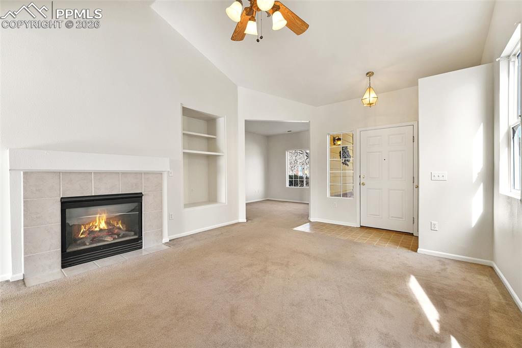 Image 7 of 28: Unfurnished living room featuring built in shelves, a ceiling fan, light co