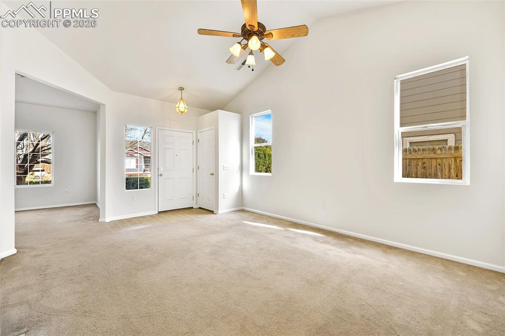 Image 8 of 28: Carpeted empty room with a ceiling fan, lofted ceiling, and healthy amount 
