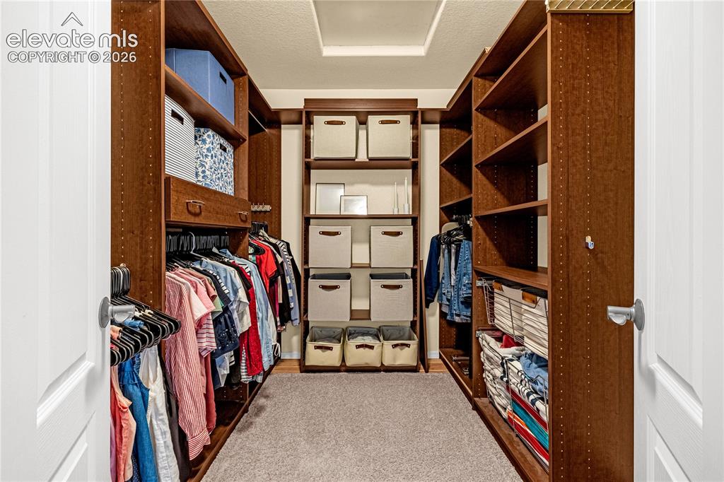Image 25 of 41: Primary walk in closet with custom built-ins