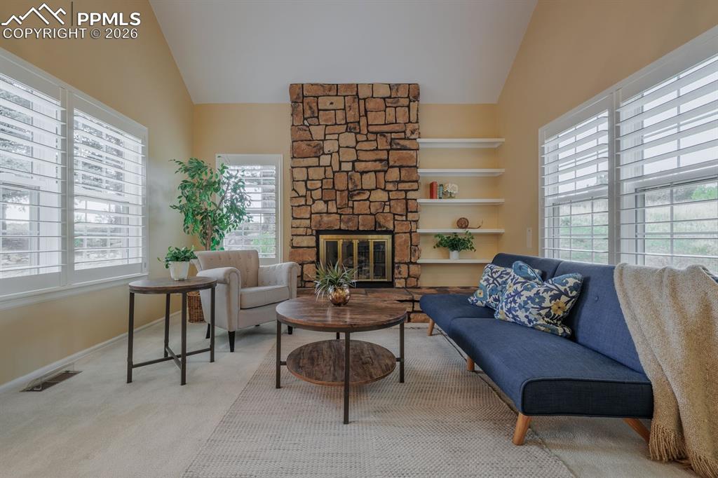 Image 12 of 47: Floor to ceiling stone surround on gas fireplace with hearth. Custom shutte