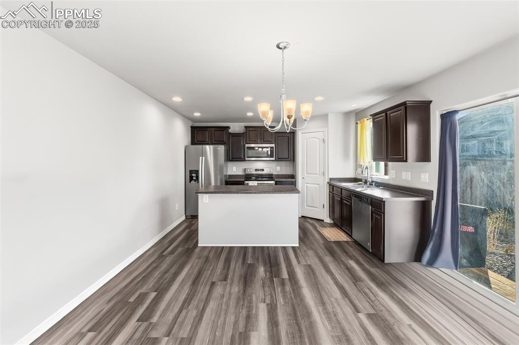 Image 22 of 48: Kitchen featuring dark brown cabinets, dark countertops, dark wood finished