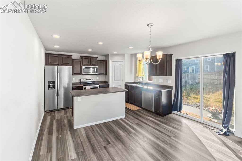 Image 23 of 48: Kitchen with stainless steel appliances, dark brown cabinets, a center isla