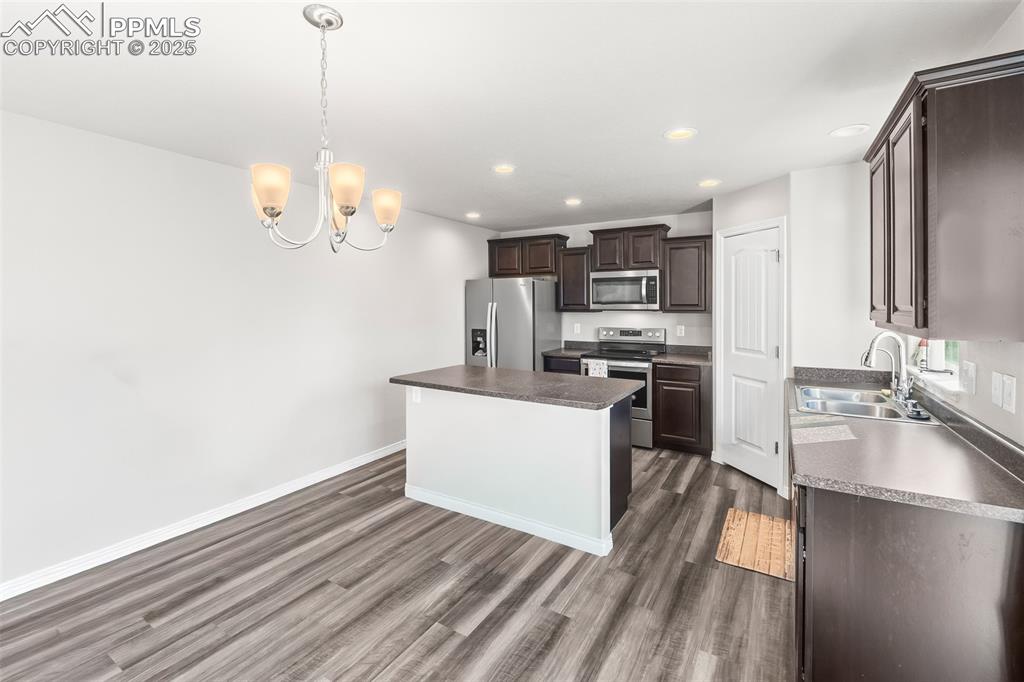Image 24 of 48: Kitchen featuring dark brown cabinetry, appliances with stainless steel fin