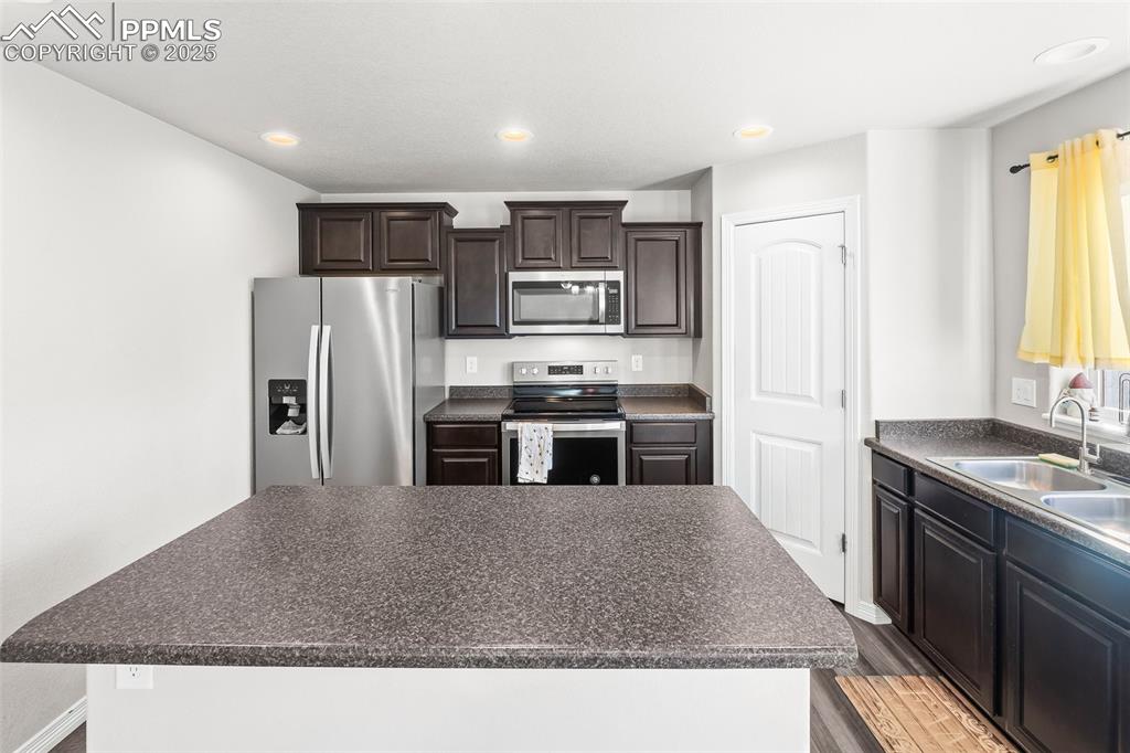 Image 26 of 48: Kitchen with appliances with stainless steel finishes, dark countertops, re